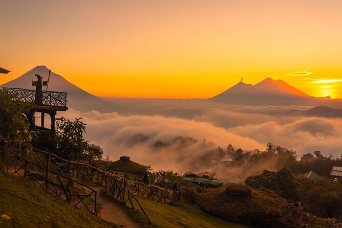 Two volcano cones standing above a sea of cloud at sunrise